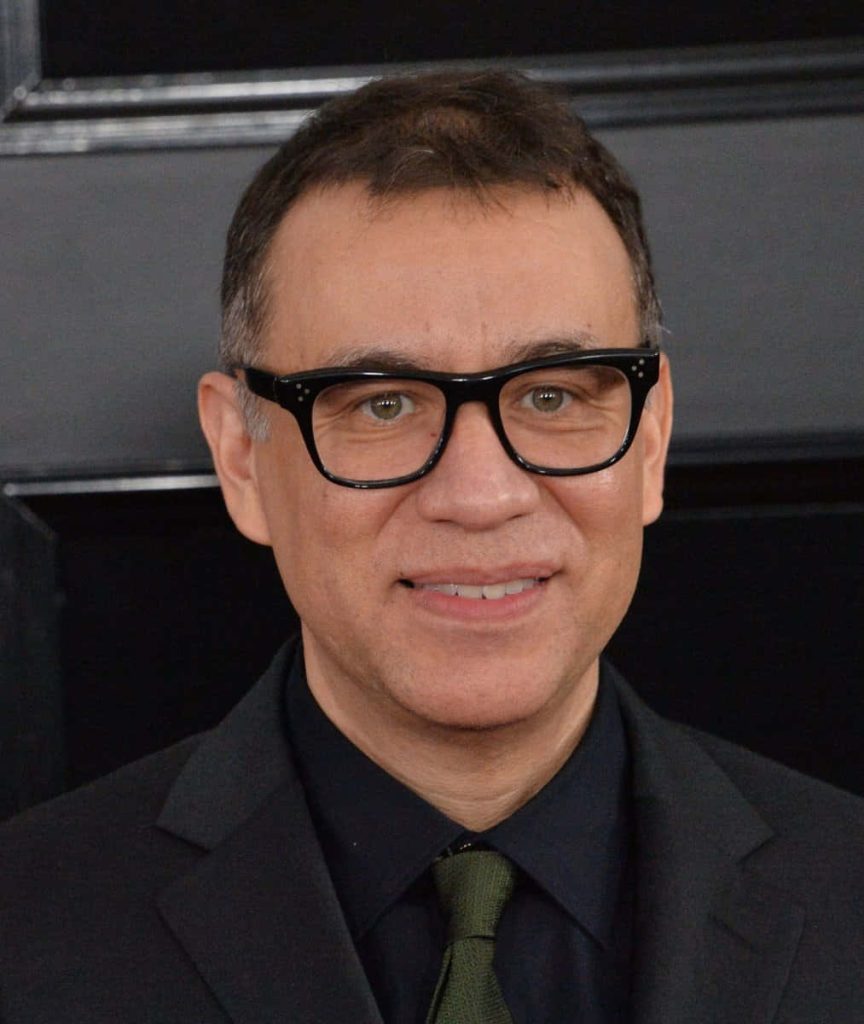 Sharp close-up portrait of Fred Armisen in black suit and glasses on minimalist black background Wallpaper