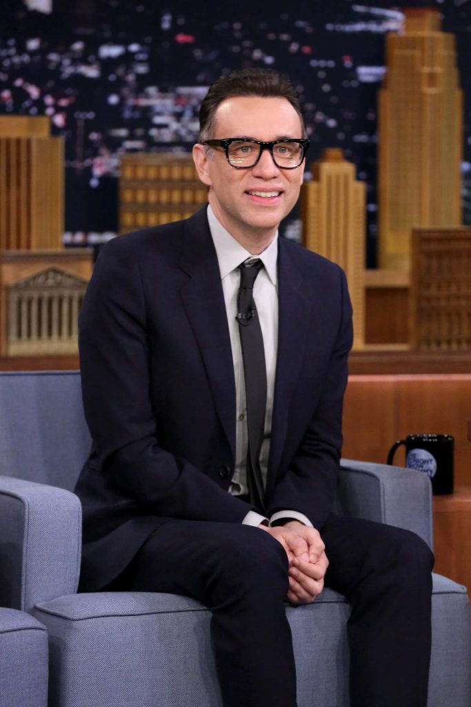 Fred Armisen smiling in dark suit and glasses during The Tonight Show interview on studio couch Wallpaper