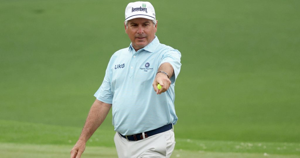 Fred Couples in blue striped polo and cap pointing on golf course holding yellow ball wallpaper