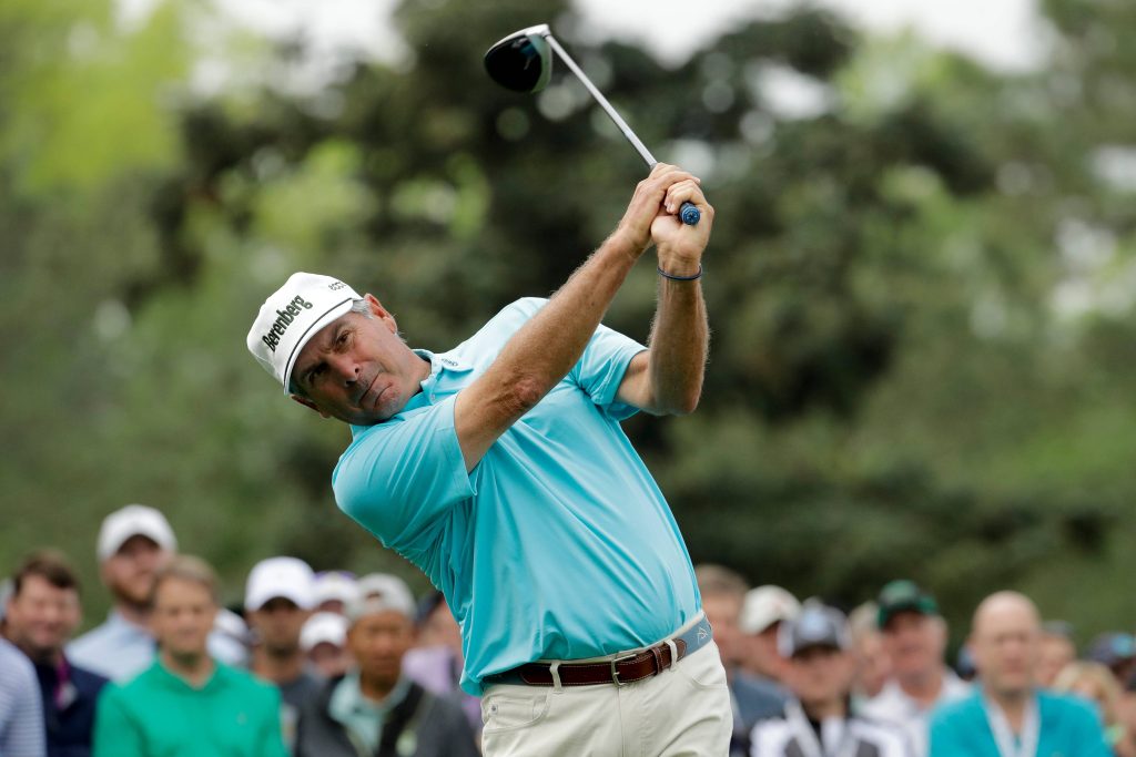 Fred Couples powerful golf swing in light blue polo and Berenberg cap with blurred crowd background Wallpaper