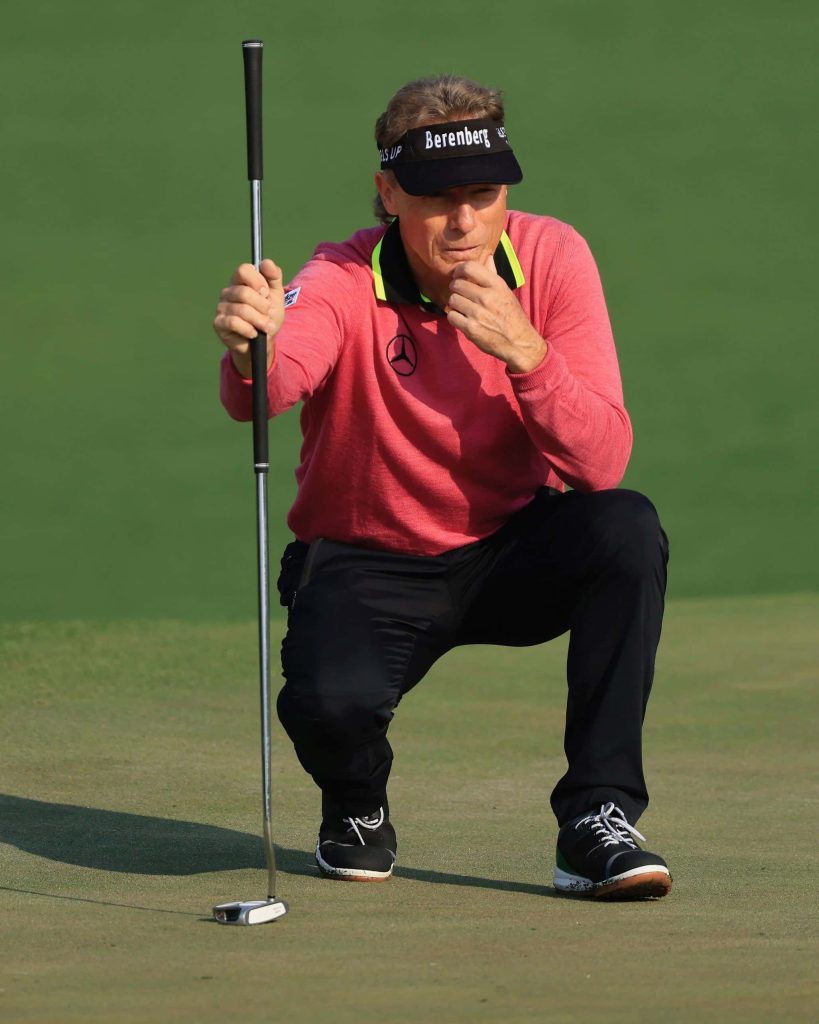 Professional golfer Fred Funk focused studying putt on golf green wearing pink sweater and visor Wallpaper