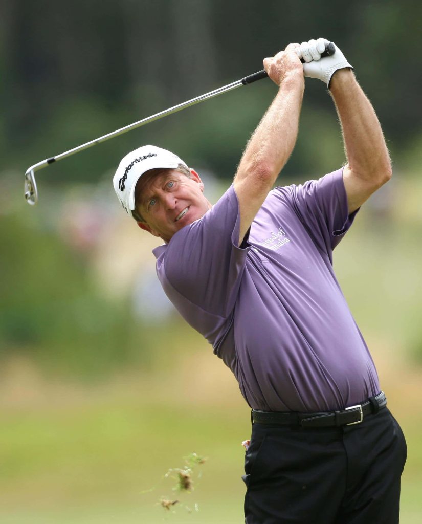 Fred Funk golf swing follow-through in lavender polo and white TaylorMade cap on green course Wallpaper