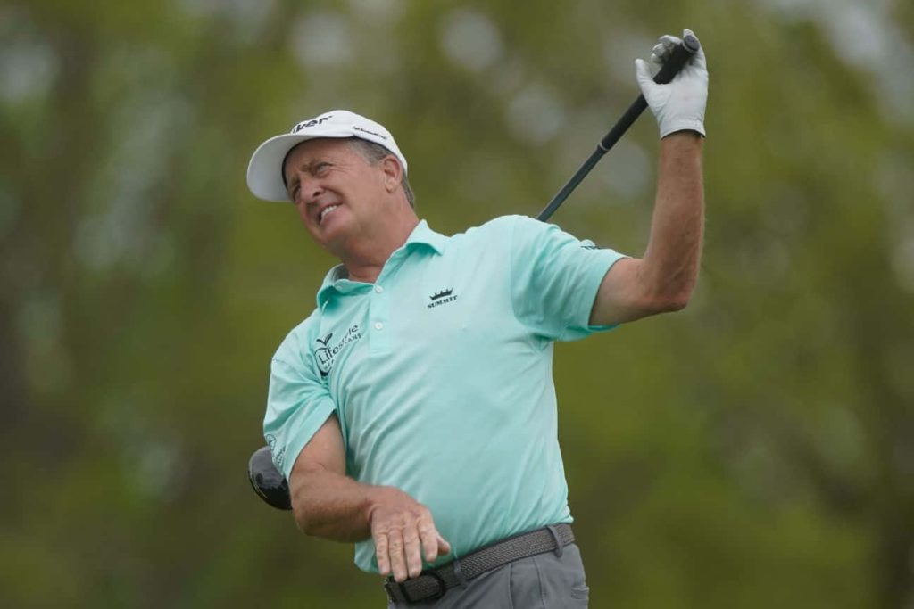 Professional golfer Fred Funk mid-swing in mint green polo on lush golf course background Wallpaper