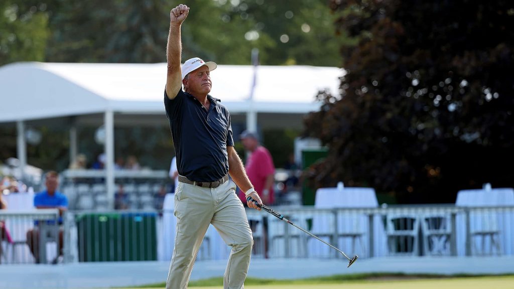 Golf pro Fred Funk fist pumps on the green in black polo and khakis during tournament win Wallpaper