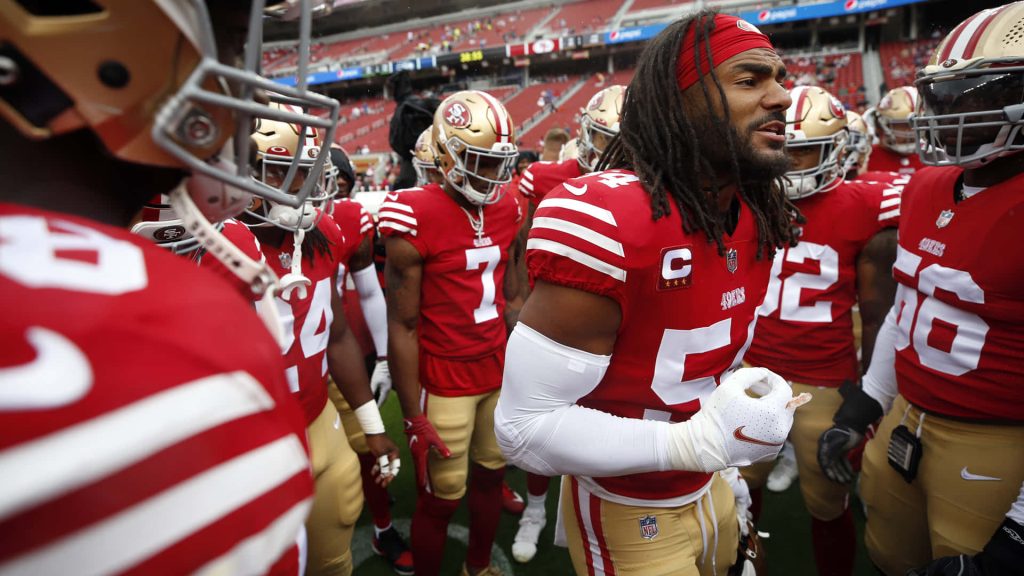Fred Warner leads San Francisco 49ers huddle in red and gold intense NFL team spirit wallpaper
