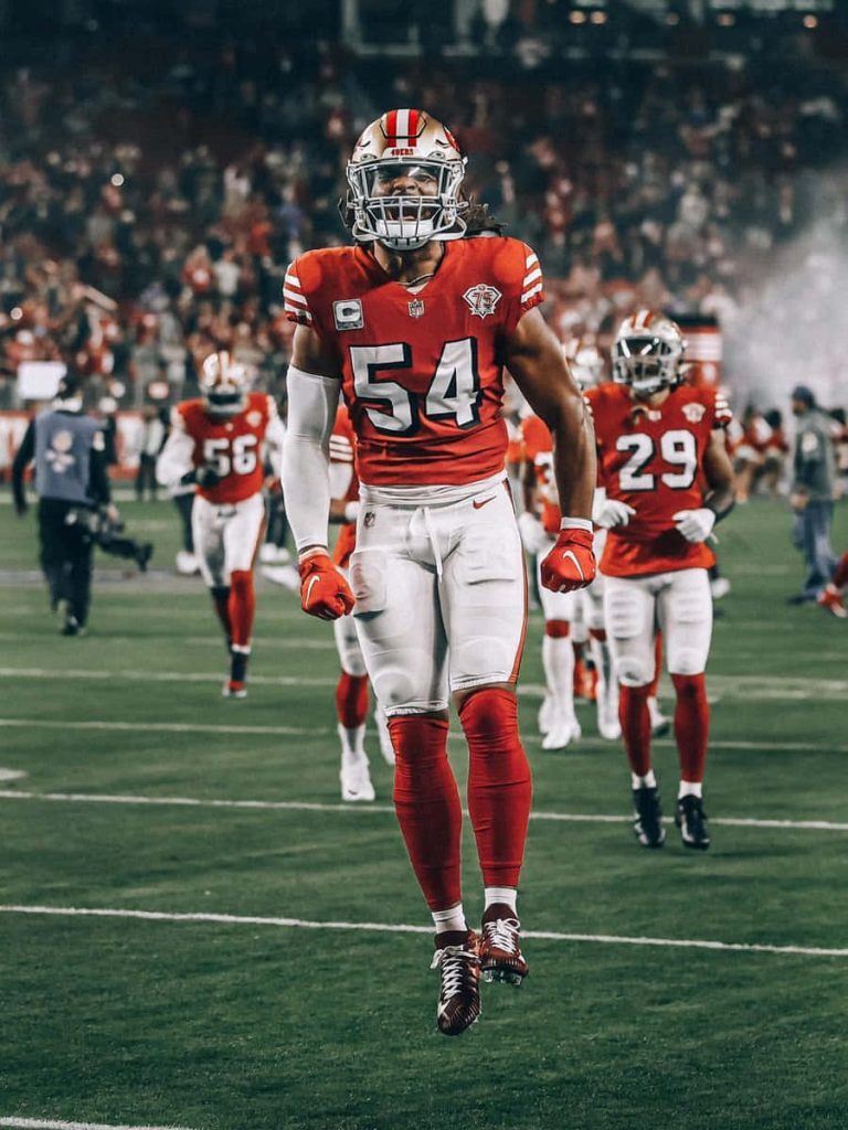 Fred Warner 49ers linebacker in red gold jersey vibrant stadium game action wallpaper background