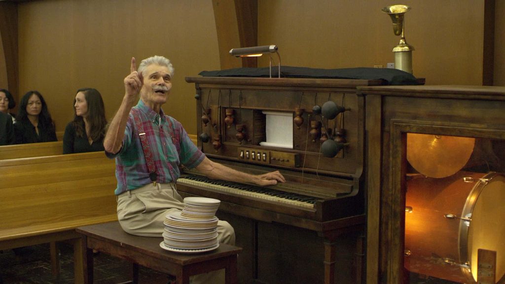 Fred Willard in plaid shirt with antique instrument and plates warm cinematic wallpaper background