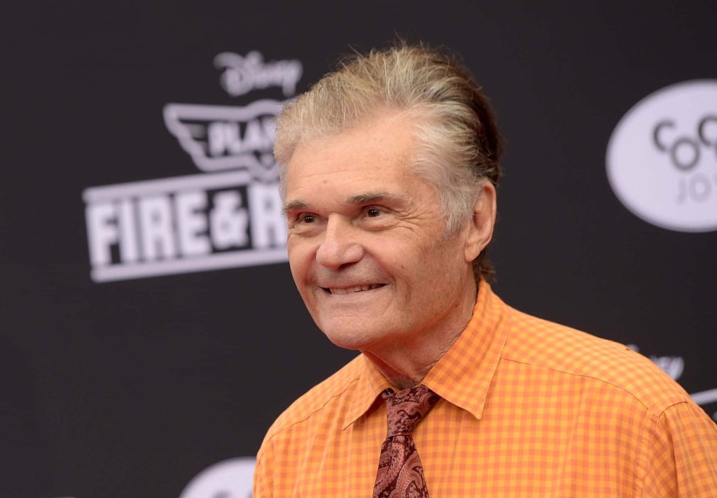 Fred Willard vibrant portrait smiling at red carpet in orange plaid shirt and tie wallpaper background