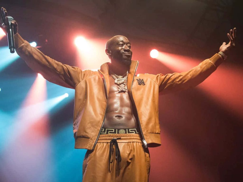 Freddie Gibbs live performance wallpaper rapper stage arms outstretched tan leather jacket joggers