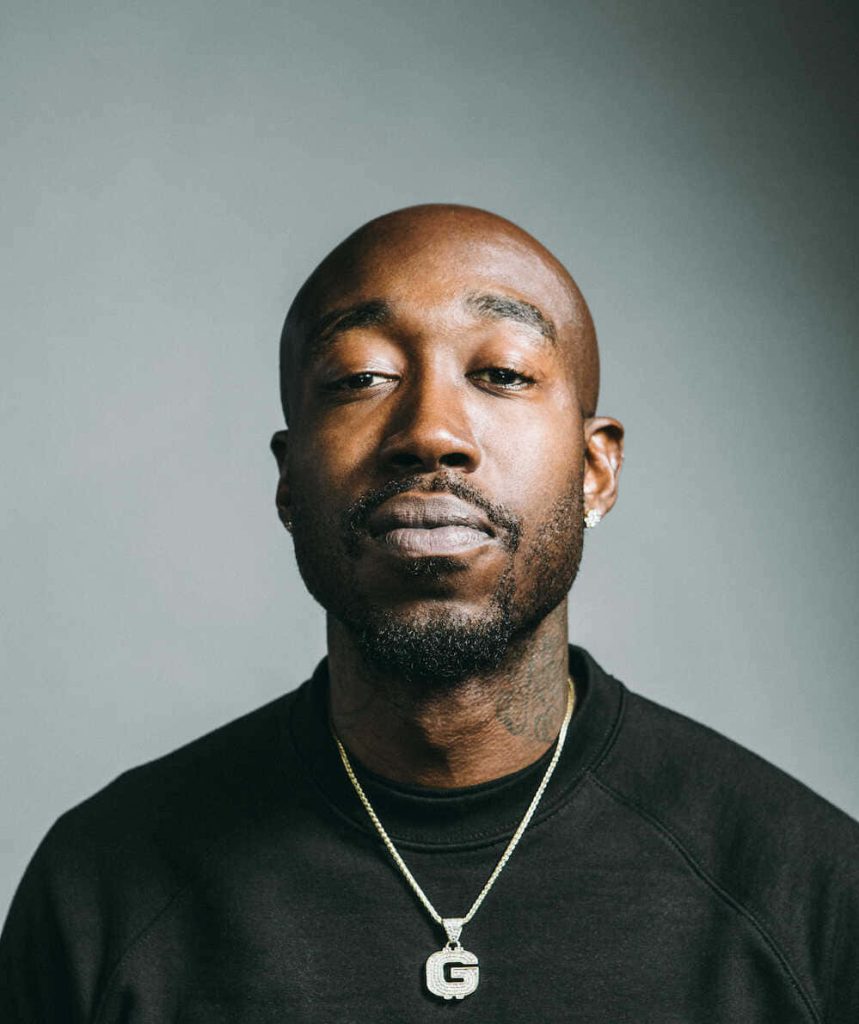 Freddie Gibbs portrait black sweatshirt diamond G chain neutral grey background studio lighting Wallpaper