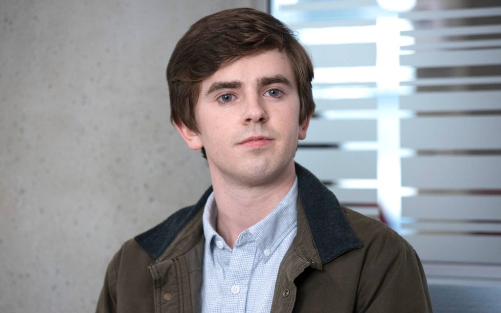 Freddie Highmore portrait in plaid shirt and olive jacket calm gentle expression office background Wallpaper