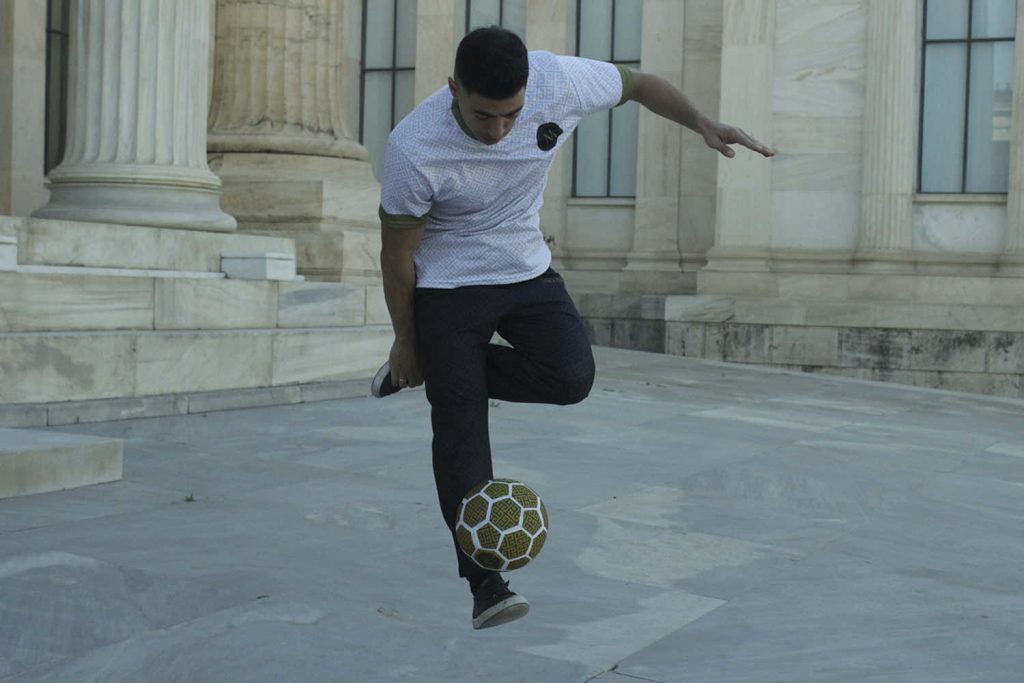 Freestyle soccer athlete performs trick in front of neoclassical marble architecture with soft lighting Wallpaper