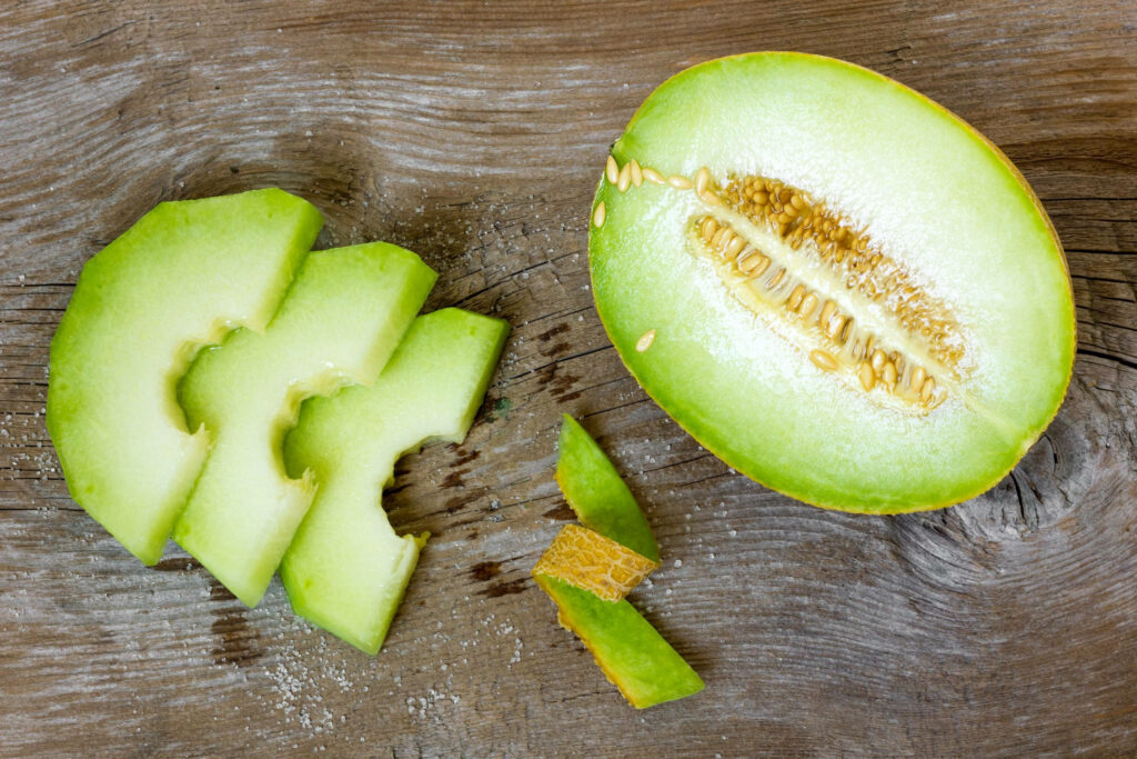 Fresh Ash Gourd Display with Slices and Seeds on Rustic Wood Wallpaper