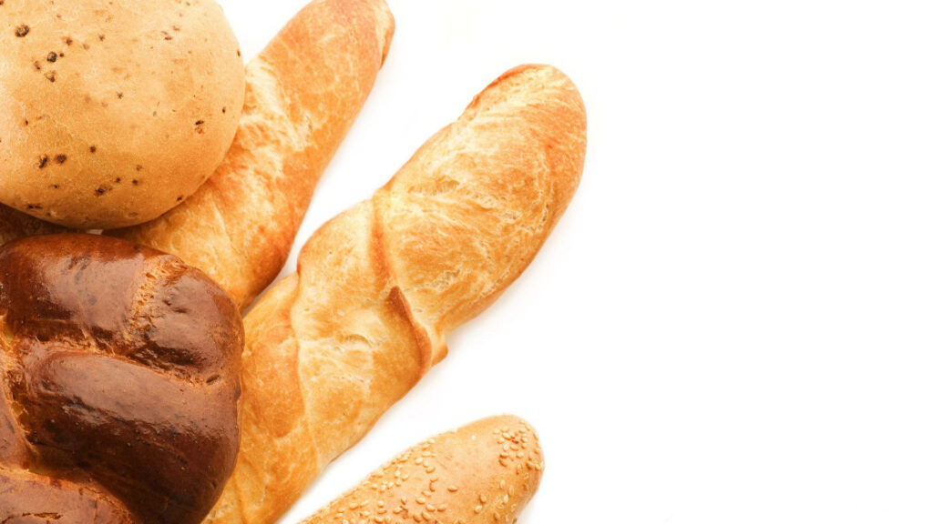 Fresh baked breads assortment including baguettes rolls and sesame loaves on white background Wallpaper
