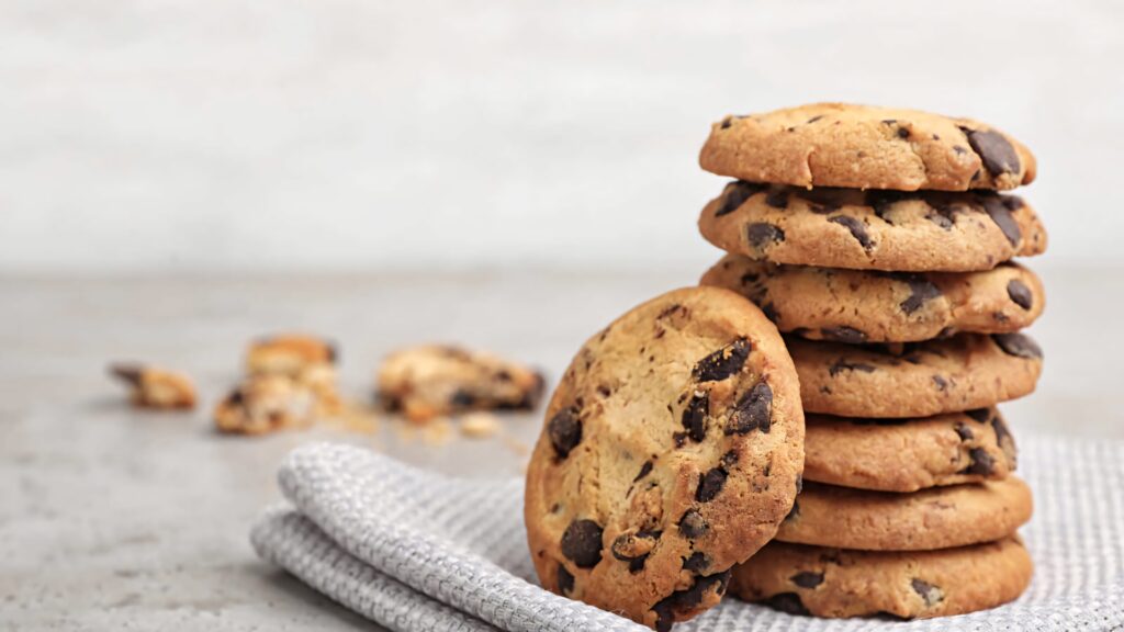 Stack of fresh baked golden chocolate chip cookies on soft cloth with rich chocolate chunks Wallpaper