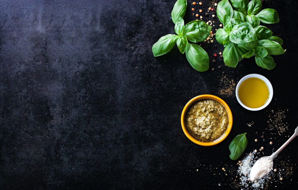 Fresh basil leaves with pesto olive oil and seasonings on rustic wooden background wallpaper