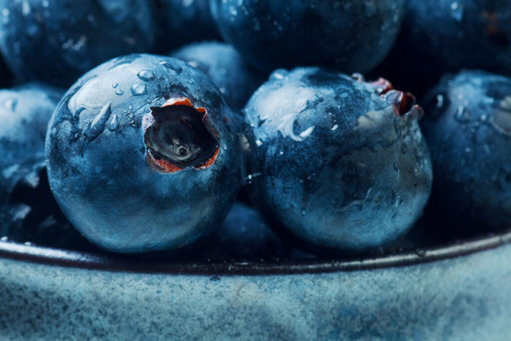 Close-up of fresh blueberries with water droplets highlighting juicy texture in natural light Wallpaper
