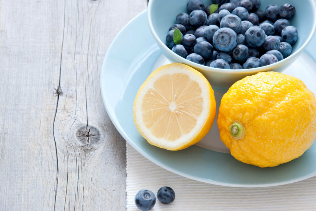 Fresh blueberries and whole halved lemon on light blue dishware rustic wooden background wallpaper
