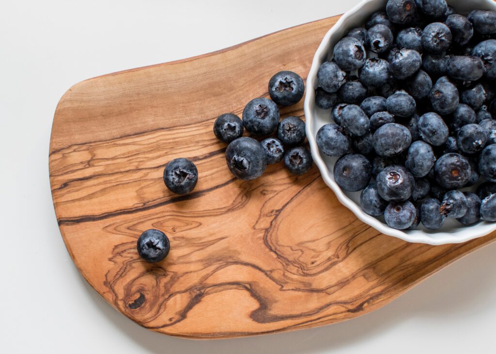 Fresh ripe blueberries on textured wooden board rich blue purple tones vibrant composition Wallpaper