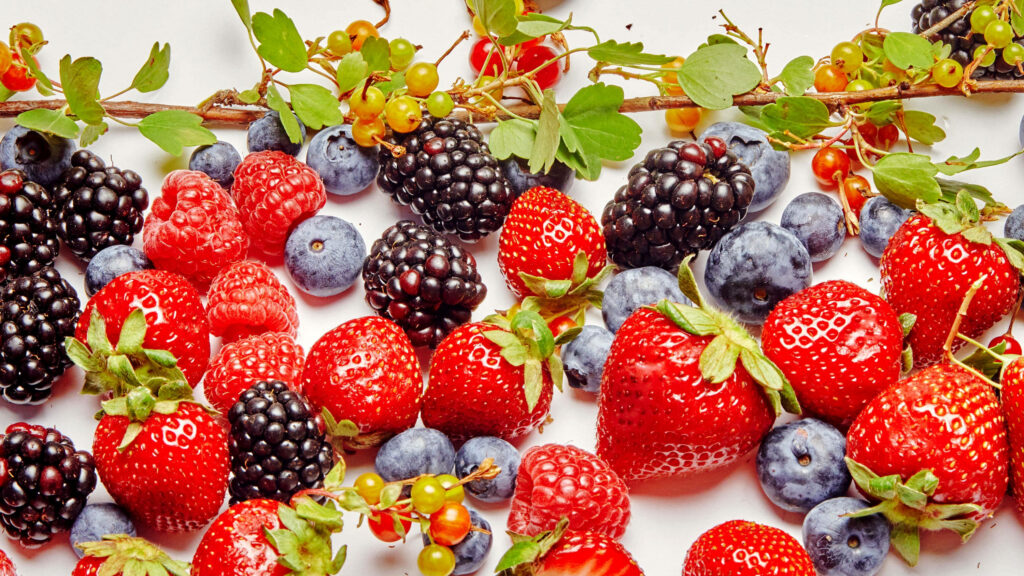 Colorful fresh boysenberries wallpaper with strawberries blueberries blackberries raspberries and leaves