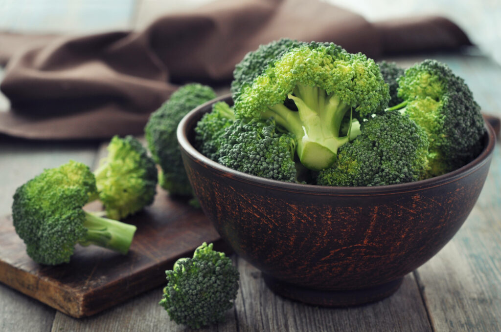 Fresh broccoli florets in rustic brown bowl on wooden surface organic farm to table background Wallpaper