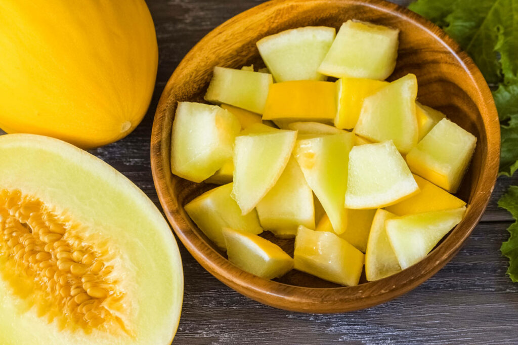 Vibrant Canary Melon Cubes in Wooden Bowl - Fresh Wallpaper Background