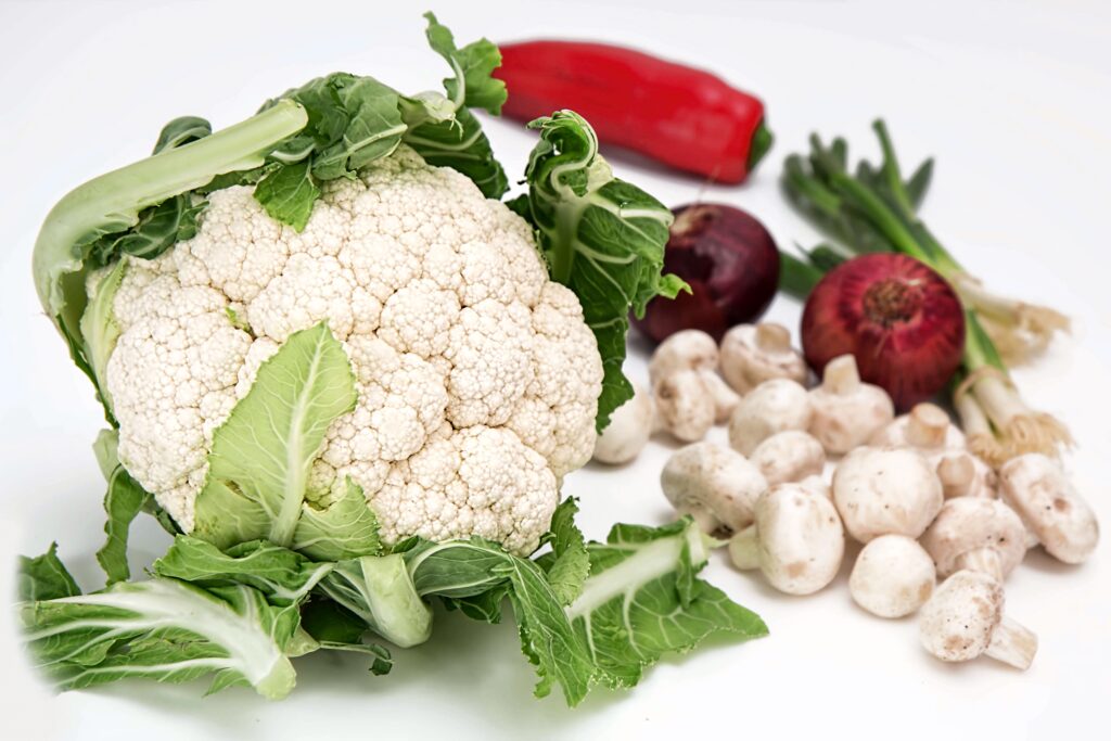 Fresh cauliflower with mushrooms red onion spring onions and red chili on white background Wallpaper