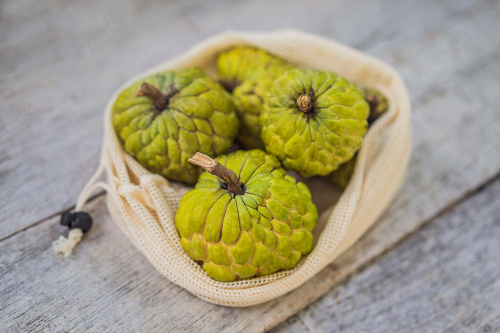 Cherimoya fruits in natural string bag on rustic wood fresh organic eco-friendly wallpaper background