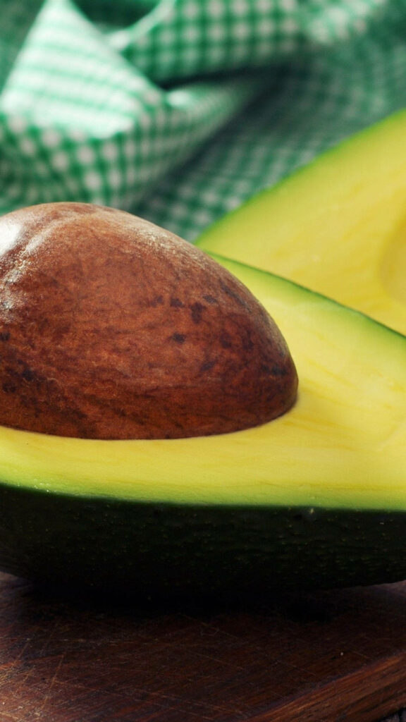 Vibrant Ripe Avocado Portrait: Fresh Green Flesh & Seed on Wallpaper