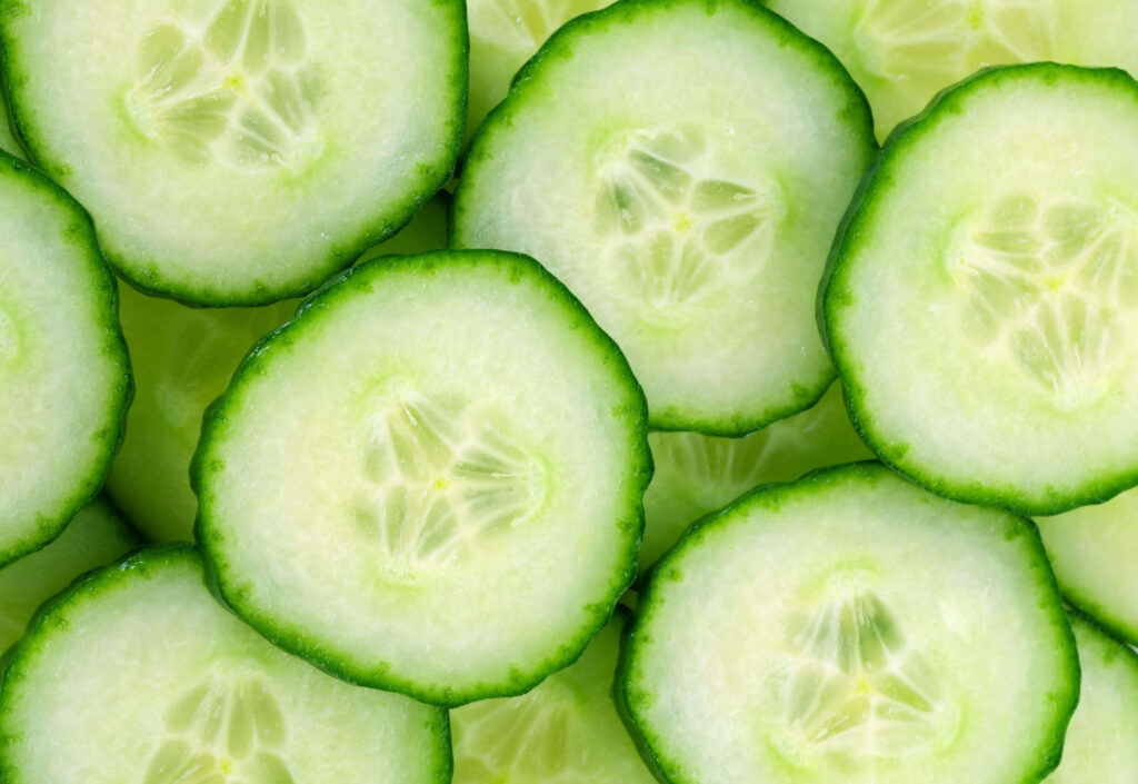 Close-up of fresh cucumber slices with crisp green edges and translucent centers background wallpaper
