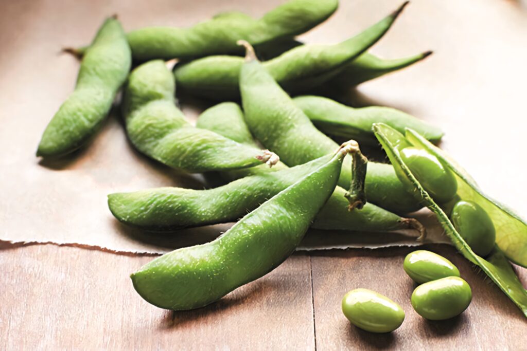 Close-up of fresh vibrant green edamame pods on rustic wood highlighting natural texture and freshness Wallpaper