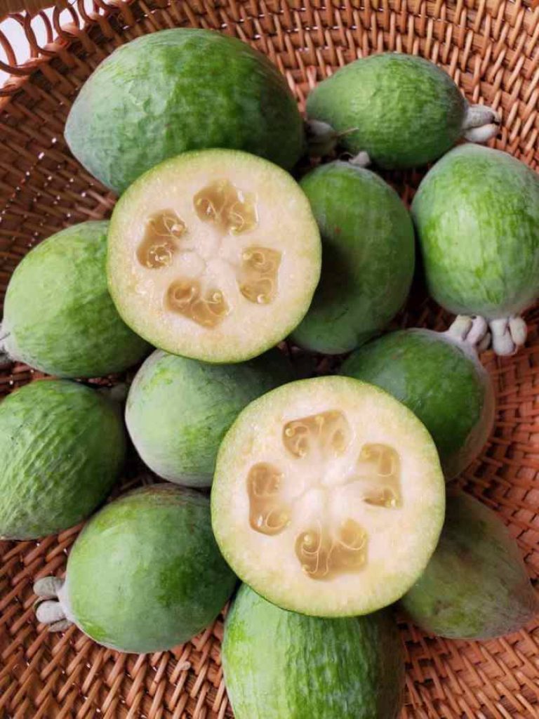 Fresh Feijoa fruits whole and halved in a rustic basket with translucent jelly interiors bright light Wallpaper