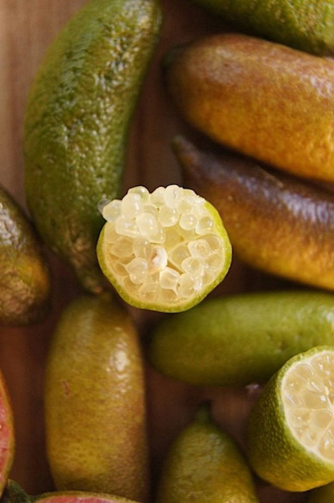 Macro top view of fresh finger limes whole and sliced with translucent caviar citrus vesicles wallpaper