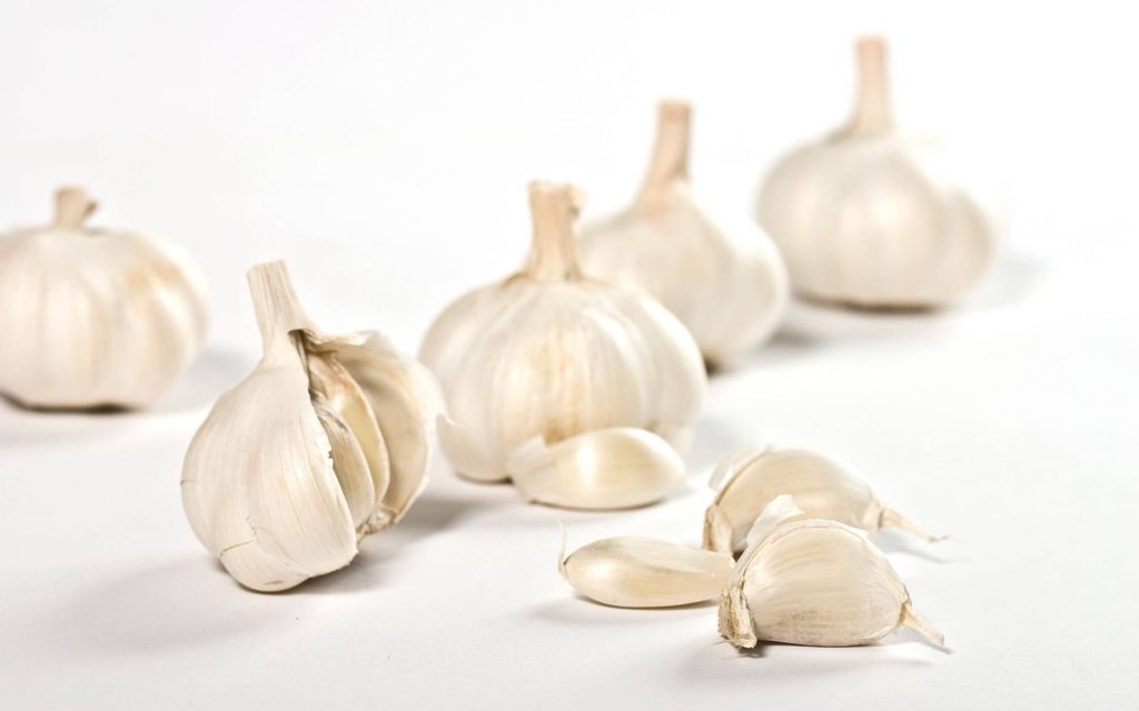 Fresh garlic bulbs and cloves on bright white background with natural texture in studio lighting Wallpaper