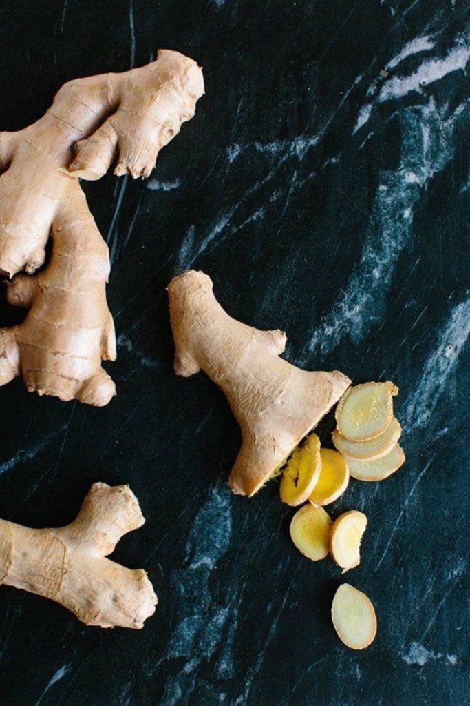 Fresh ginger roots and slices on dark black marble background high contrast culinary wallpaper