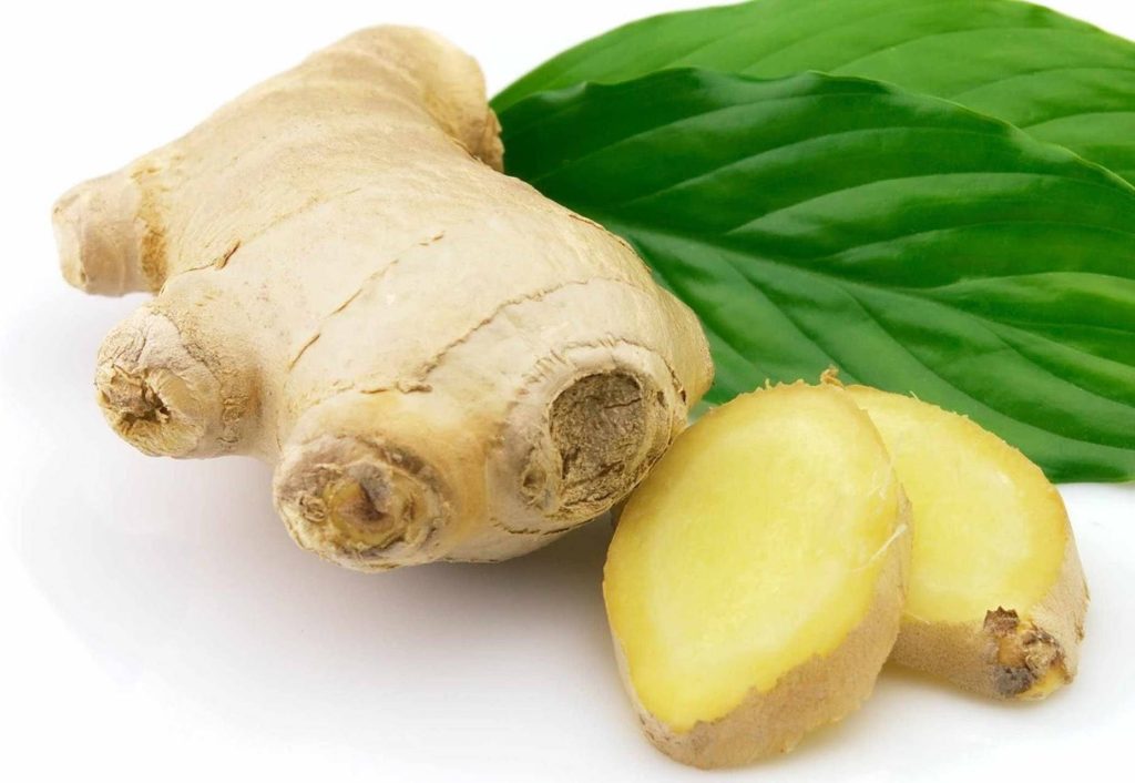 Fresh sliced ginger root with green leaves on white background high resolution studio photo Wallpaper