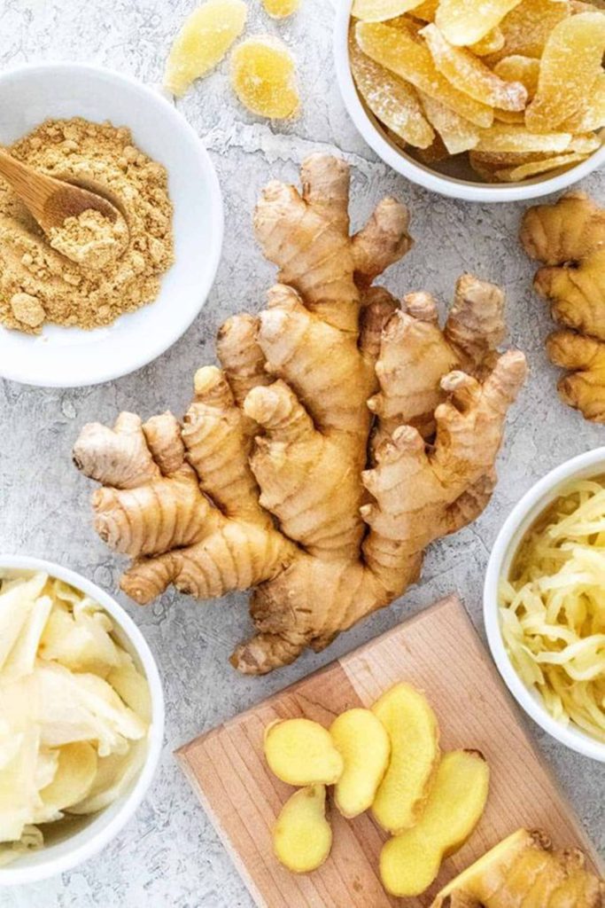Fresh whole ginger root with ground shredded crystallized ginger on rustic board background Wallpaper