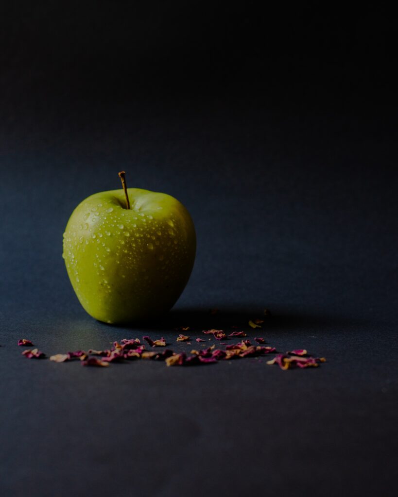 Vibrant Green Apple with Water Droplets & Dried Petals Wallpaper