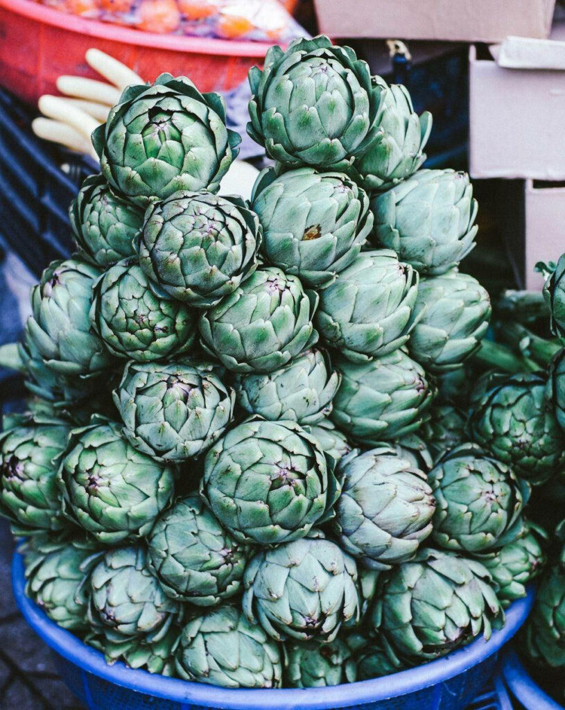 Fresh green artichokes stacked showing natural texture vibrant vegetable wallpaper background