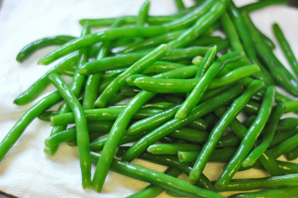 Fresh green beans spread on white cloth showcasing crisp texture and vibrant color wallpaper