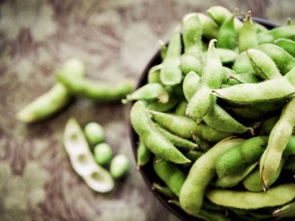 Close-up of rustic bowl with fresh green edamame beans on blurred earthy background wallpaper
