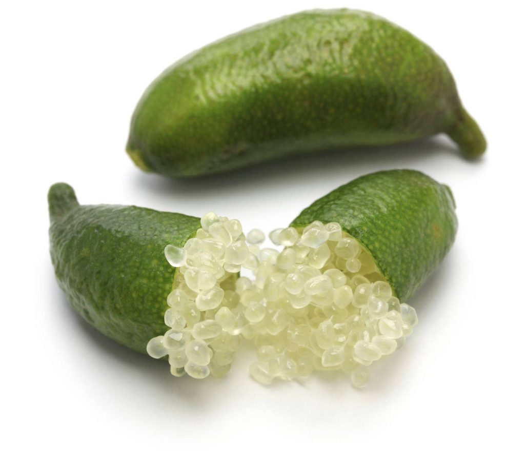Close-up of fresh green finger limes one whole and one sliced showing translucent caviar vesicles on white background Wallpaper