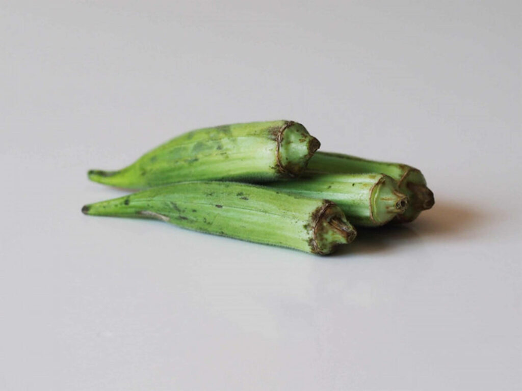Fresh Green Okra Cluster on White Table - Natural Wallpaper Background