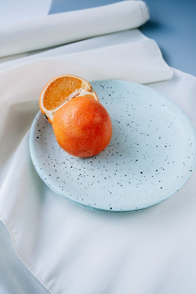 Fresh Oranges on Blue Speckled Plate: Elegant Wallpaper Design