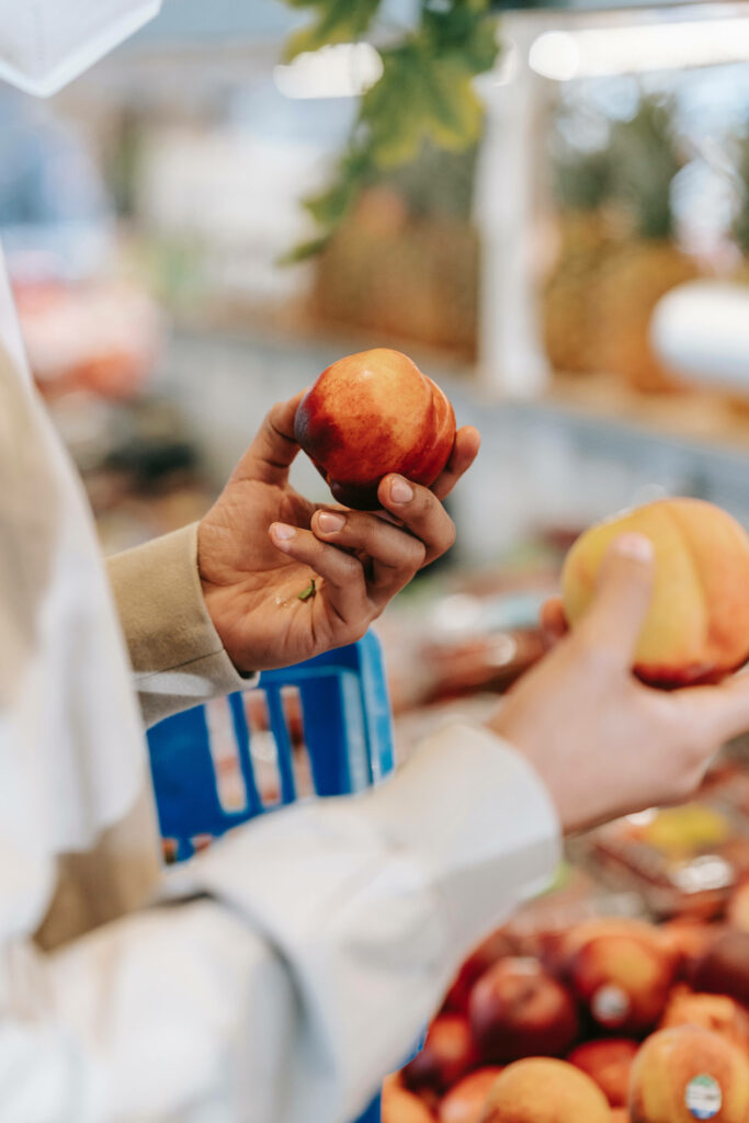 Choosing Fresh Nectarines: A Grocery Store Shopping Scene Wallpaper