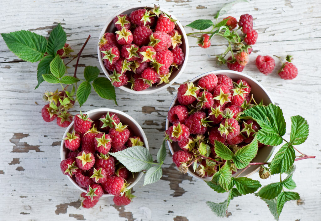Fresh Raspberries Wallpaper: Rustic Table with Berries & Green Leaves