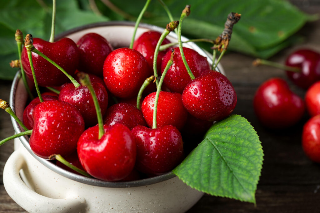 Fresh red cherries with water droplets in white ramekin on rustic wooden background summer wallpaper