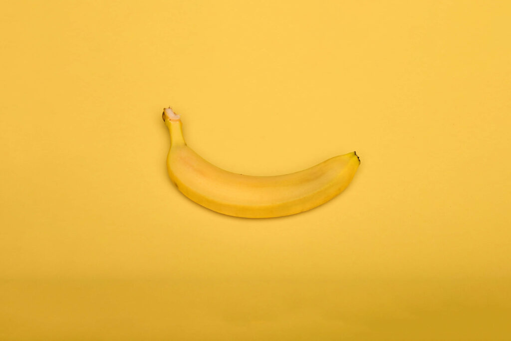 Perfectly ripe banana on vibrant yellow background fresh fruit simplicity wallpaper design