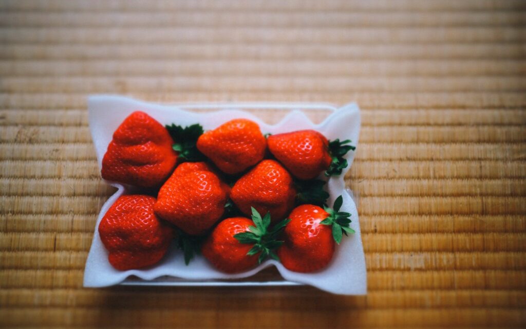 Vibrant Close-Up of Ripe Red Strawberries on Wooden Table Wallpaper
