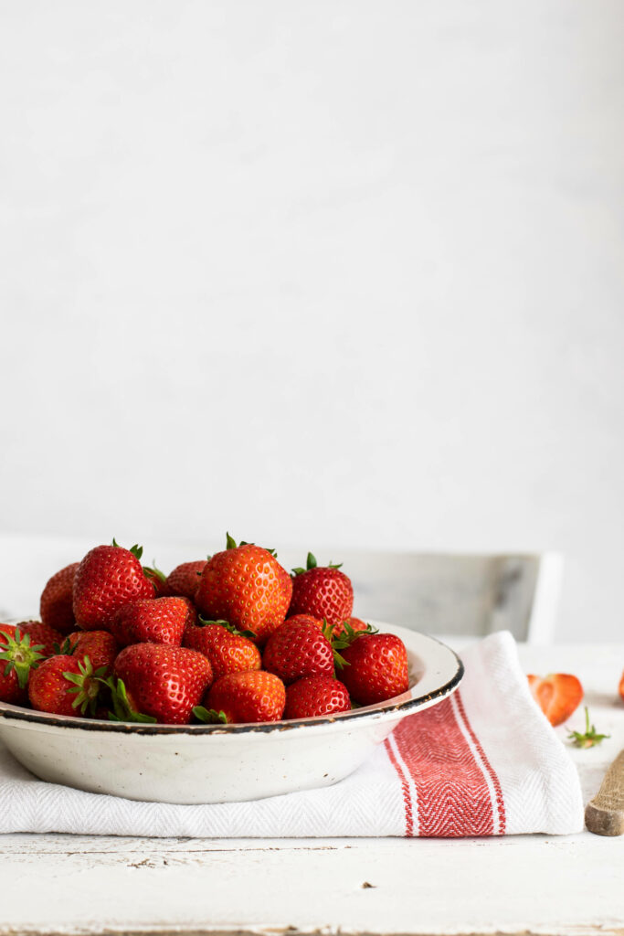 Fresh ripe strawberries neatly arranged on white plate bright background vibrant wallpaper